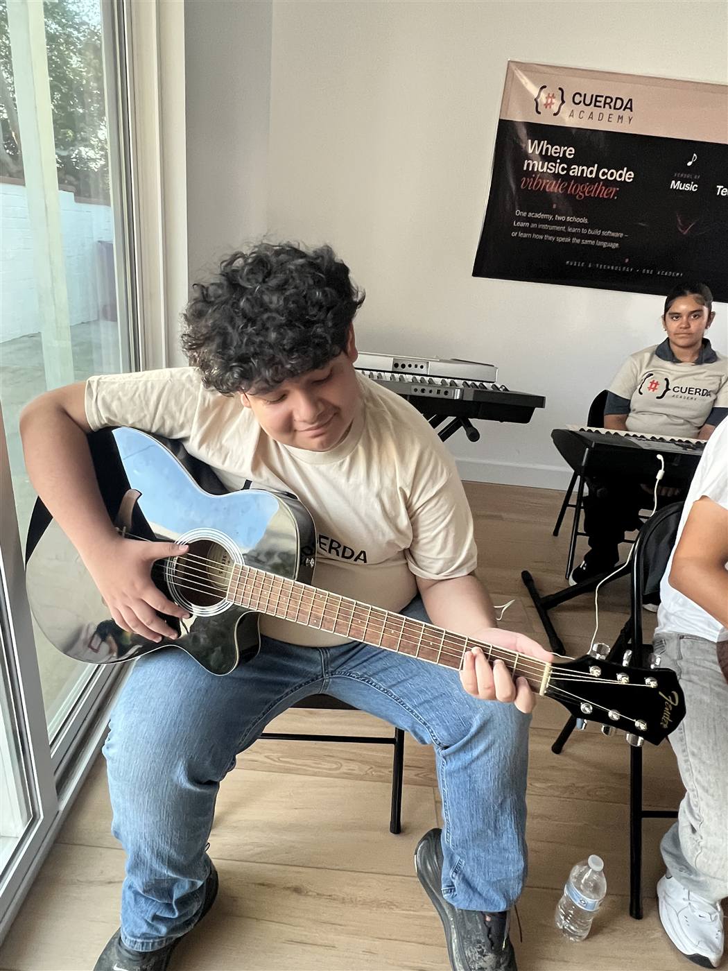 Student playing acoustic guitar at Cuerda Academy